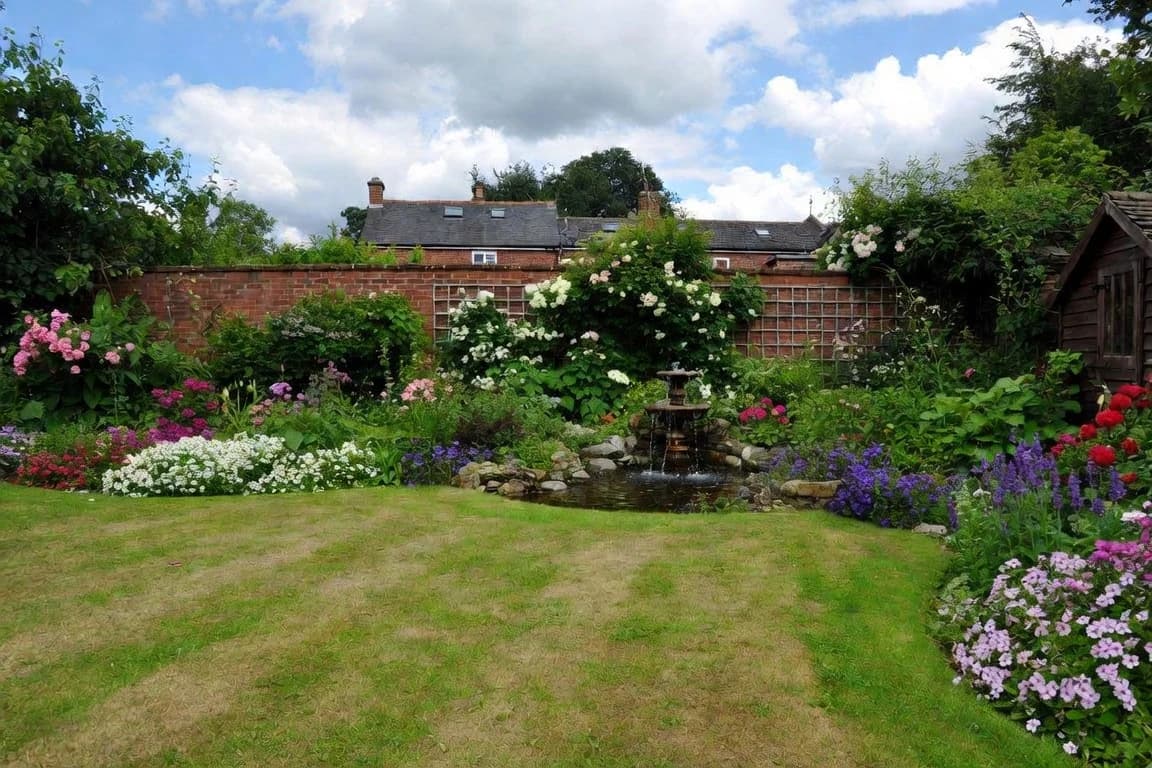 A flower-filled British garden with a pond